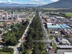 Aerial view of a tree-lined divided highway with TransMilenio buses and a pedestrian bridge in northern Bogotá