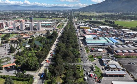 Aerial view of a tree-lined divided highway with TransMilenio buses and a pedestrian bridge in northern Bogotá