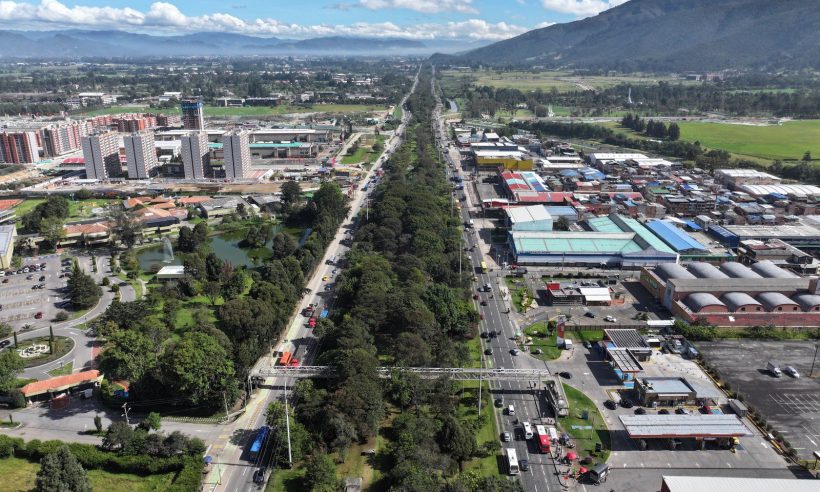 Aerial view of a tree-lined divided highway with TransMilenio buses and a pedestrian bridge in northern Bogotá