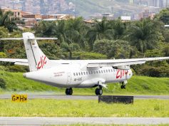 Clic ATR turboprop HK-5315 touching down on the runway at Olaya Herrera Airport, with Medellín hillside homes behind