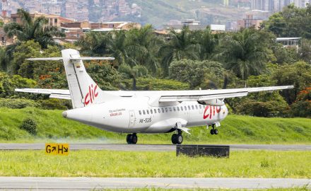 Clic ATR turboprop HK-5315 touching down on the runway at Olaya Herrera Airport, with Medellín hillside homes behind