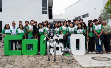 Students and adults stand behind large green and white COL5.0 letters with a humanoid robot and a robot dog in front