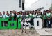 Students and adults stand behind large green and white COL5.0 letters with a humanoid robot and a robot dog in front