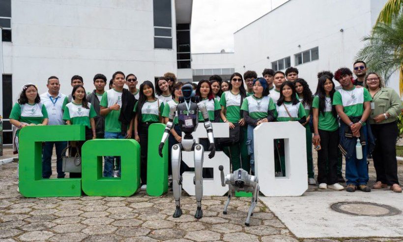 Students and adults stand behind large green and white COL5.0 letters with a humanoid robot and a robot dog in front