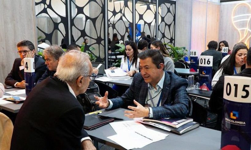 Business representatives talk across numbered tables at a trade fair matchmaking session with ProColombia table signs